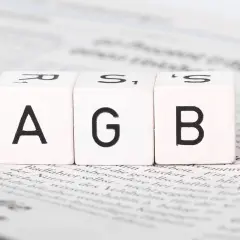 Drei Würfel mit den Buchstaben A, G, B liegen auf Zeitungstext. Ein wichtiger Schritt, um AGB zu erstellen.