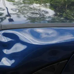 Blauer Lack mit deutlichem Hagelschaden, typisch für ein Leasingfahrzeug nach einem Unwetter.