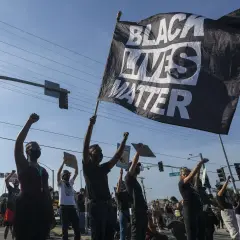 Menschen demonstrieren mit einer "Black Lives Matter"-Flagge. Die Bedeutung von Black Lives Matter ist die Forderung nach Gleichheit und Gerechtigkeit für Schwarze.