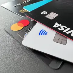 Nahaufnahme von Kreditkarten: eine schwarze Karte mit "VISA" und eine transparente Karte mit dem Mastercard-Logo.