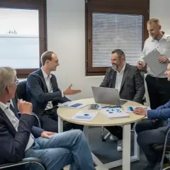 Geschäftsmänner diskutieren über Kennzahlen, wie z.B. die days payable outstanding deutsch, bei einem Meeting.