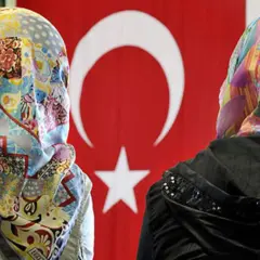 Zwei Frauen mit bunten Kopftüchern vor türkischer Flagge. Ein Bild von multikulti Deutschland.