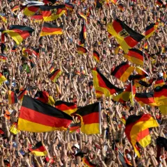 Eine jubelnde Menge mit deutschen Fahnen. Dies zeigt eine starke Form von nationalismus definition, wo die Identität durch die Nation definiert wird.