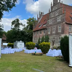 Festzelt und weiße Sitzreihen vor historischem Gebäude. Ein Anbieter für Eventausstattung hat hier alles für ein Fest vorbereitet.