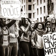 Menschen demonstrieren für Gleichheit. Ein Schild verkündet "Black Lives Matter", was die Bedeutung von BLM unterstreicht.