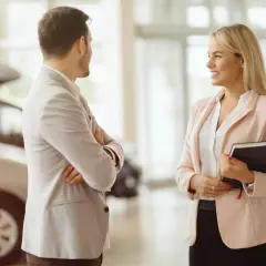 Ein Mann und eine Frau sprechen im Autohaus. Sie überlegen, ob sie ein Auto leasen oder kaufen sollen.