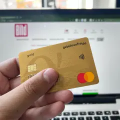 Goldene Kreditkarte mit "gebührenfrei.de" und Mastercard-Logo vor einem Laptop mit BILD-Logo. Erste Erfahrungen mit der Advanzia Bank.