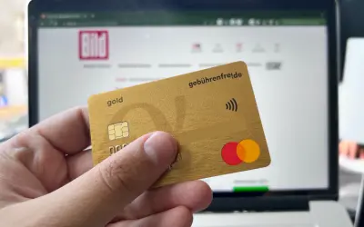 Goldene Kreditkarte mit "gebührenfrei.de" und Mastercard-Logo vor einem Laptop mit BILD-Logo. Erste Erfahrungen mit der Advanzia Bank.