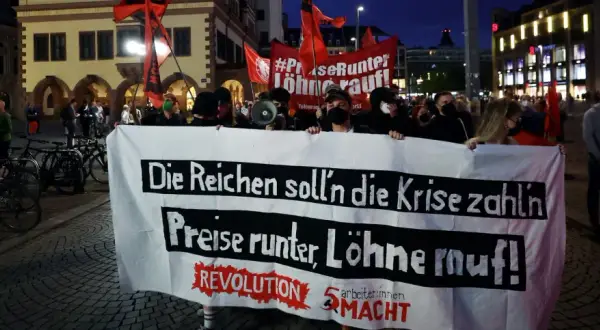 Demonstranten mit Banner "Die Reichen soll'n die Krise zahlen, Preise runter, Löhne rauf!" zeigen die politische polarisierung definition.