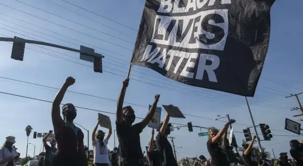 Menschen demonstrieren mit einer "Black Lives Matter"-Flagge. Die Bedeutung von Black Lives Matter ist die Forderung nach Gleichheit und Gerechtigkeit für Schwarze.