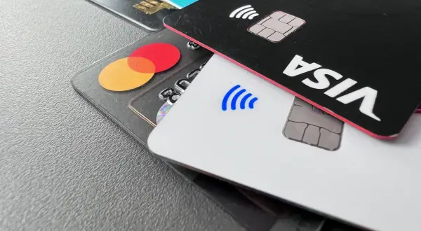 Nahaufnahme von Kreditkarten: eine schwarze Karte mit "VISA" und eine transparente Karte mit dem Mastercard-Logo.