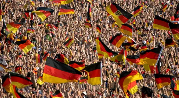 Eine jubelnde Menge mit deutschen Fahnen. Dies zeigt eine starke Form von nationalismus definition, wo die Identität durch die Nation definiert wird.