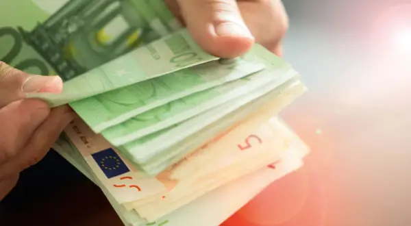 Hände zählen Euro-Scheine. Die Frage, wie oft kann man 10.000 Euro einzahlen ohne Nachweis, bleibt offen.