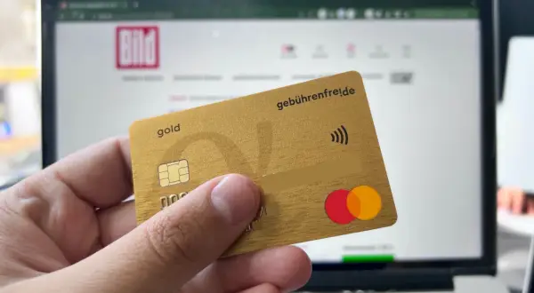 Goldene Kreditkarte mit "gebührenfrei.de" und Mastercard-Logo vor einem Laptop mit BILD-Logo. Erste Erfahrungen mit der Advanzia Bank.