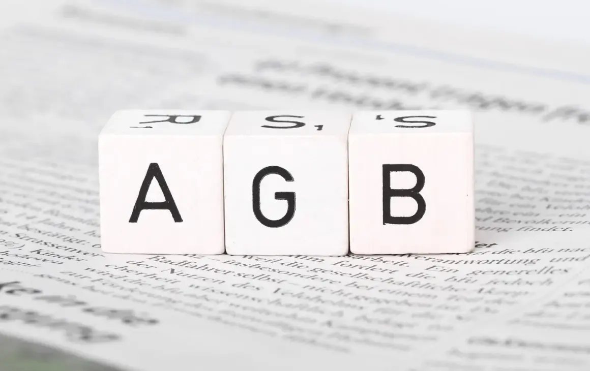 Drei Würfel mit den Buchstaben A, G, B liegen auf Zeitungstext. Ein wichtiger Schritt, um AGB zu erstellen.