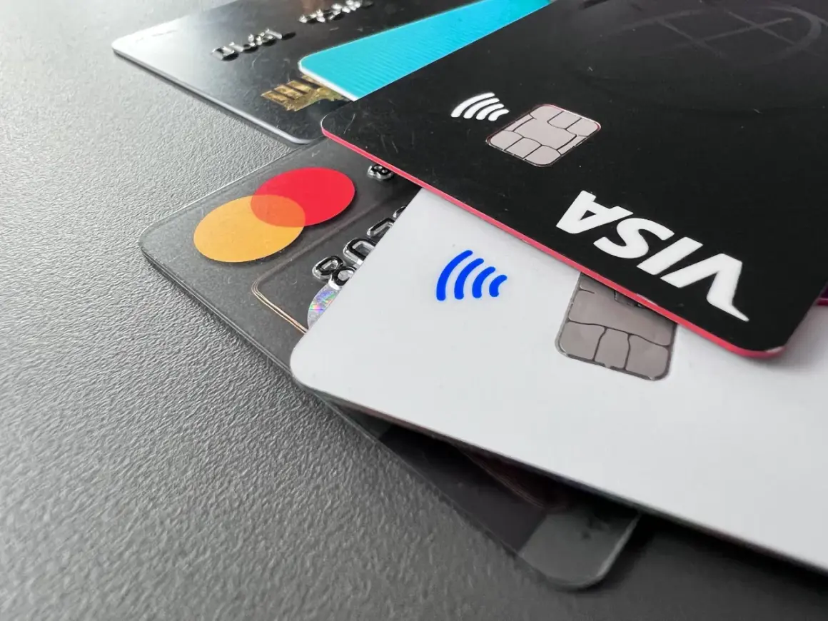 Nahaufnahme von Kreditkarten: eine schwarze Karte mit "VISA" und eine transparente Karte mit dem Mastercard-Logo.