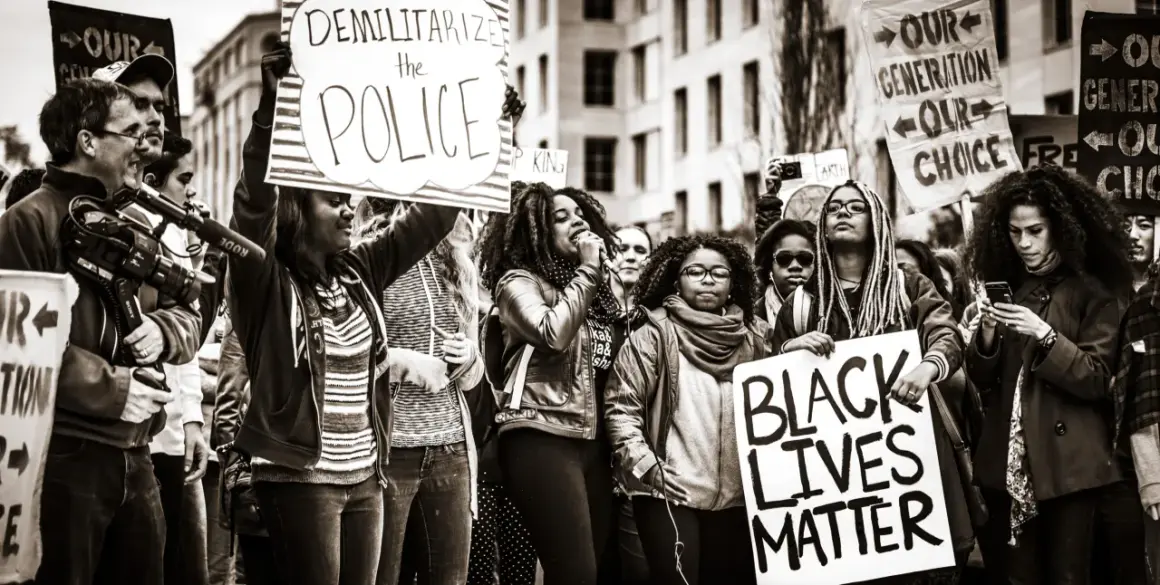Menschen demonstrieren für Gleichheit. Ein Schild verkündet "Black Lives Matter", was die Bedeutung von BLM unterstreicht.