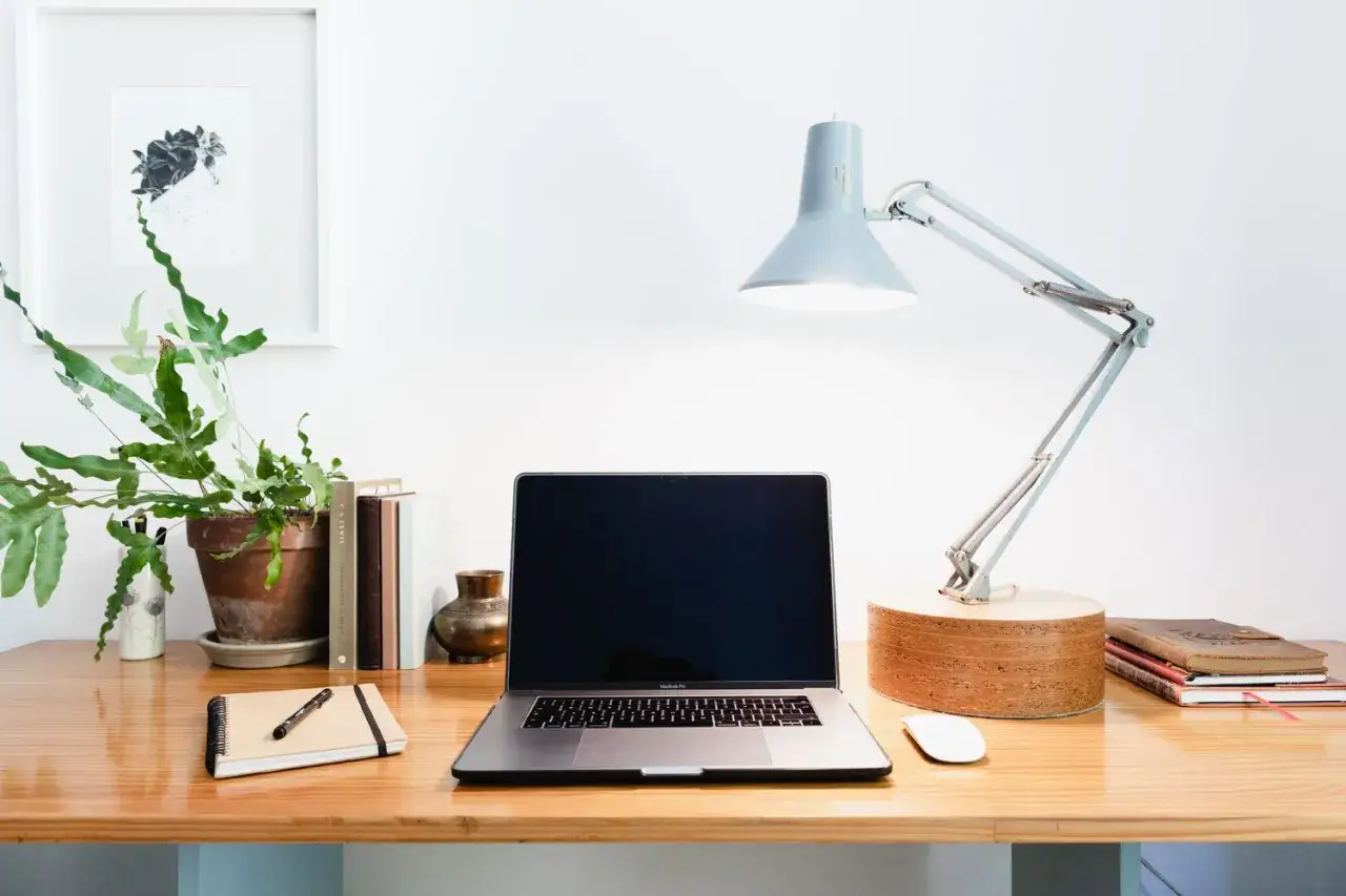 Ein home office mit Laptop, Lampe, Pflanze und Büchern. Perfekt für produktives Arbeiten.