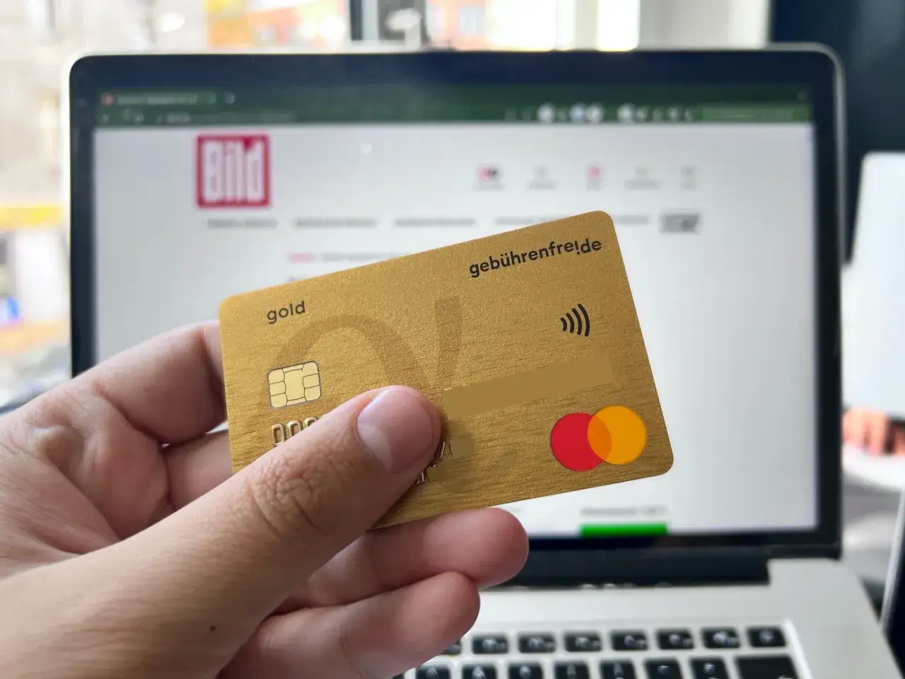 Goldene Kreditkarte vor Laptop mit BILD-Logo. Erste Advanzia Bank Erfahrungen gesammelt.
