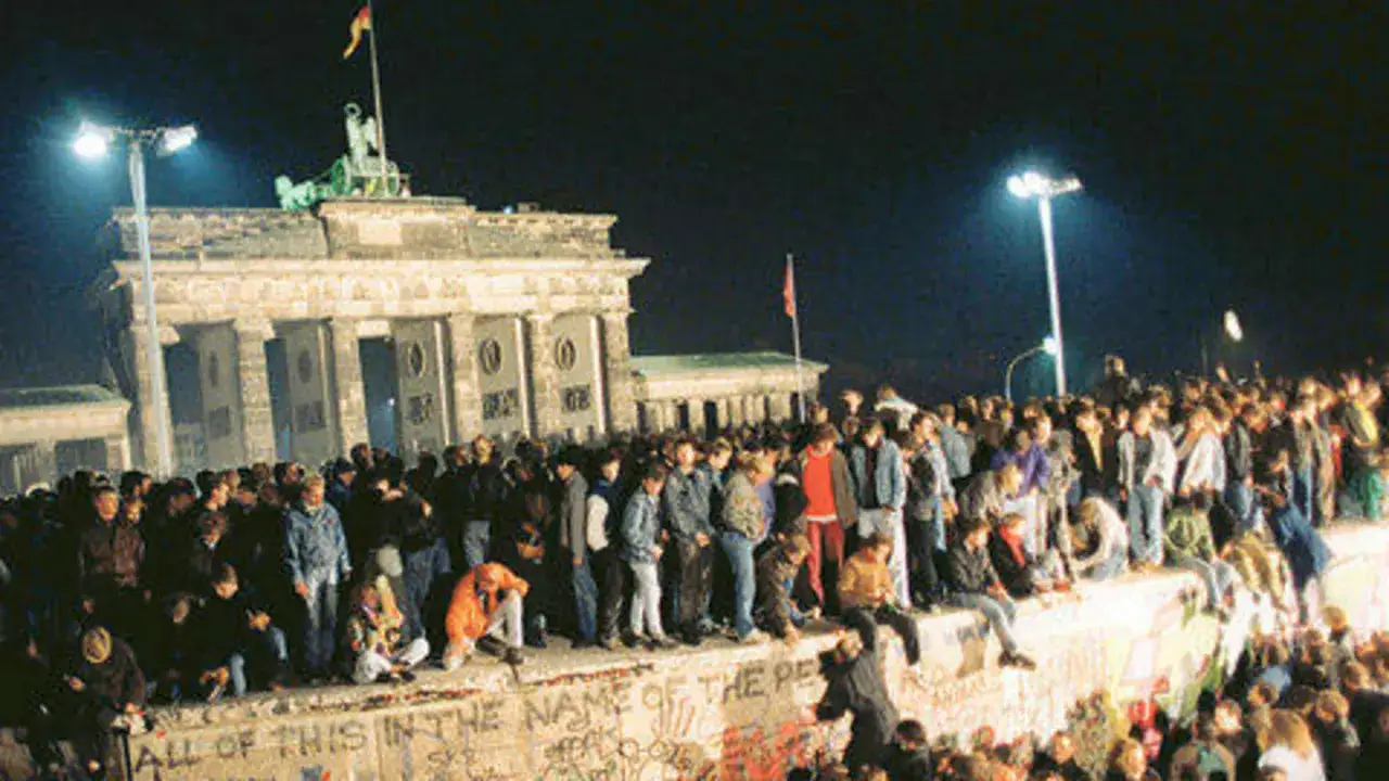 Menschen feiern am Brandenburger Tor. Die Mauer ist gefallen, ein Symbol daf&uuml;r, wer den kalten Krieg gewonnen hat.