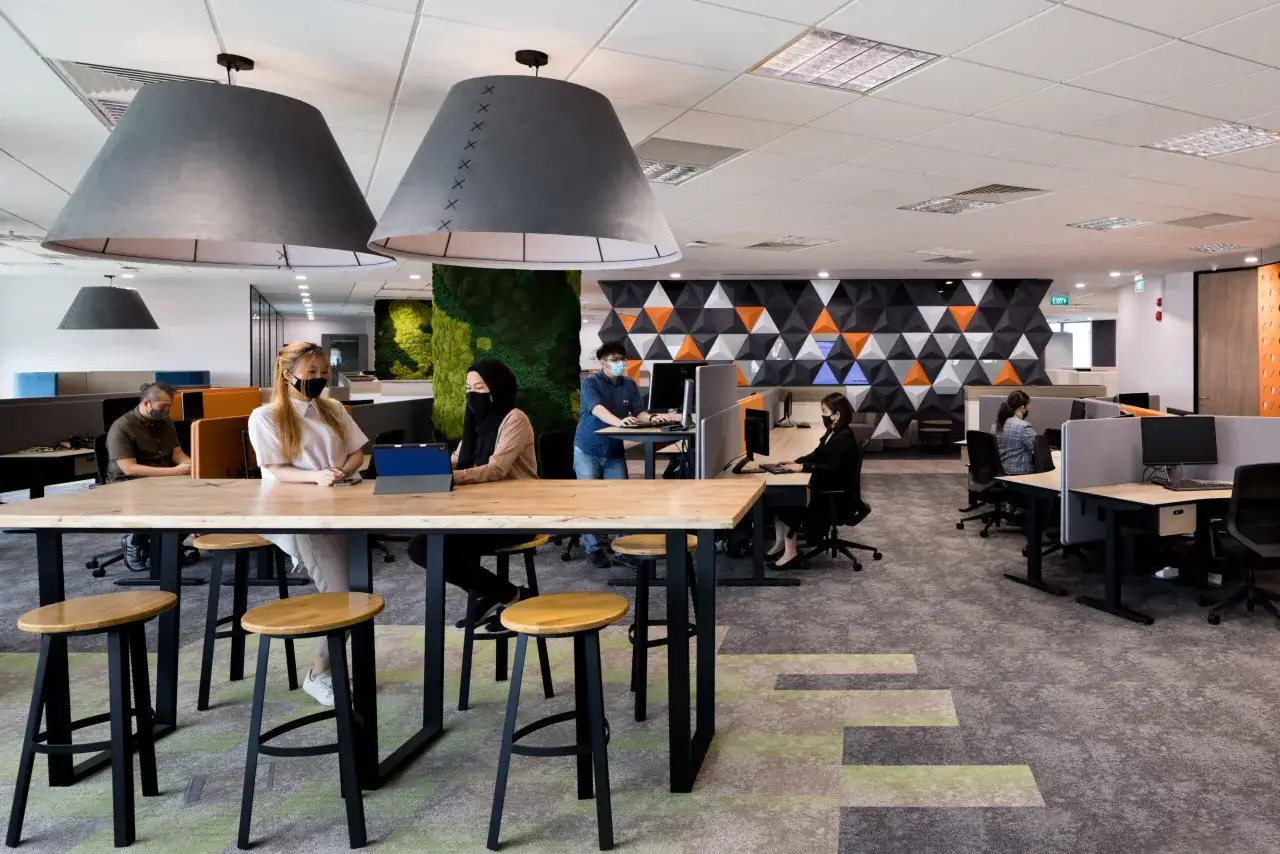 Menschen arbeiten in einem modernen B&uuml;ro mit einer agilen arbeitsweise. Gro&szlig;e Lampen und gr&uuml;ne Moosw&auml;nde schaffen eine angenehme Atmosph&auml;re.