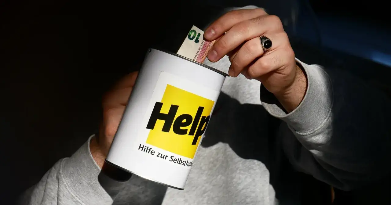 H&auml;nde legen Geld in eine Spendenb&uuml;chse mit der Aufschrift 