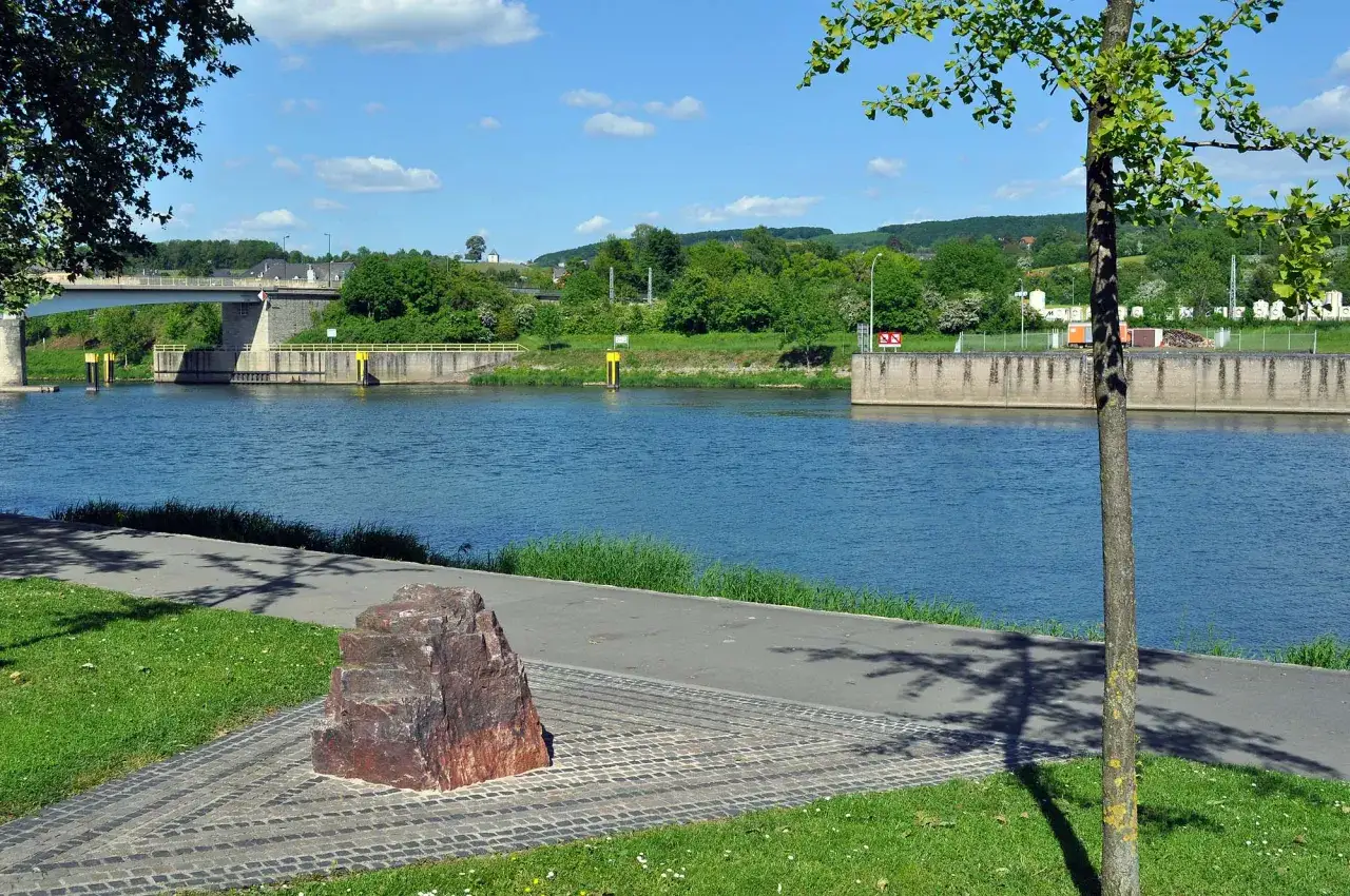 Ein Flussufer mit einem Denkmal, einer Brücke und Schleusen. Hier ist, wo Schengen liegt, ein Ort der Freiheit.