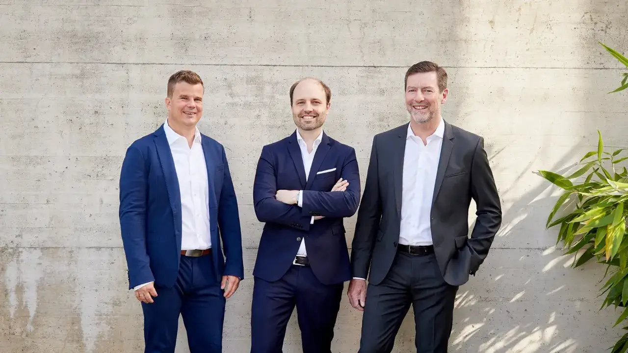 Drei M&auml;nner in Anz&uuml;gen stehen vor einer Betonwand. Sie sind bereit, als Berater zu werden und ihre Expertise zu teilen.