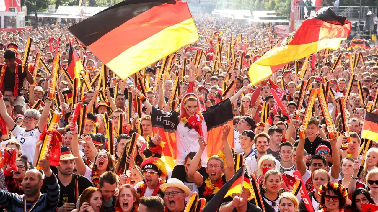 Eine jubelnde Menge mit Deutschlandflaggen und Fanges&auml;ngen, ein Ausdruck von Nationalismus, der die Einheit und Leidenschaft f&uuml;r das Land zeigt.